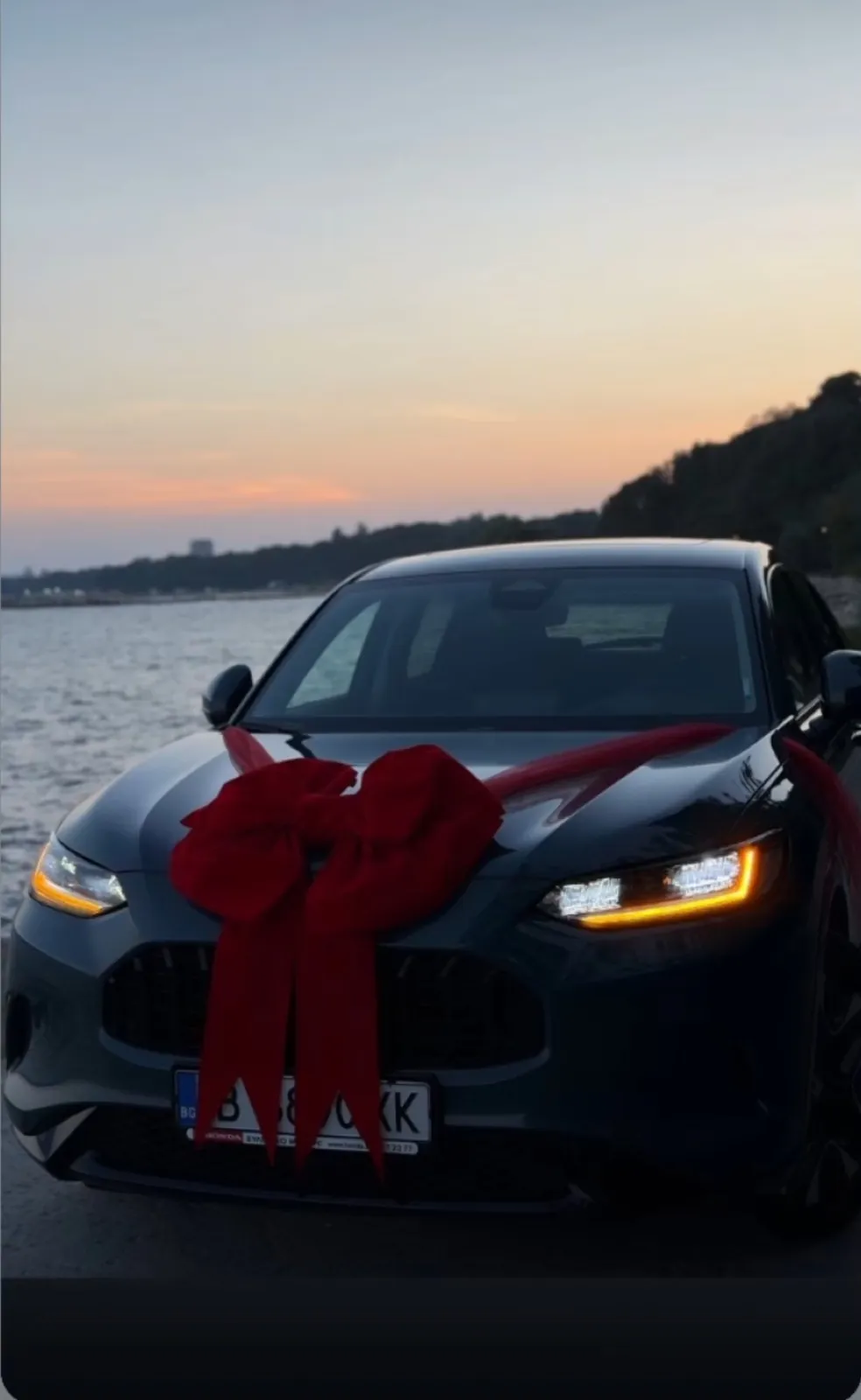 Honda с червена панделка на фона на морски залез
