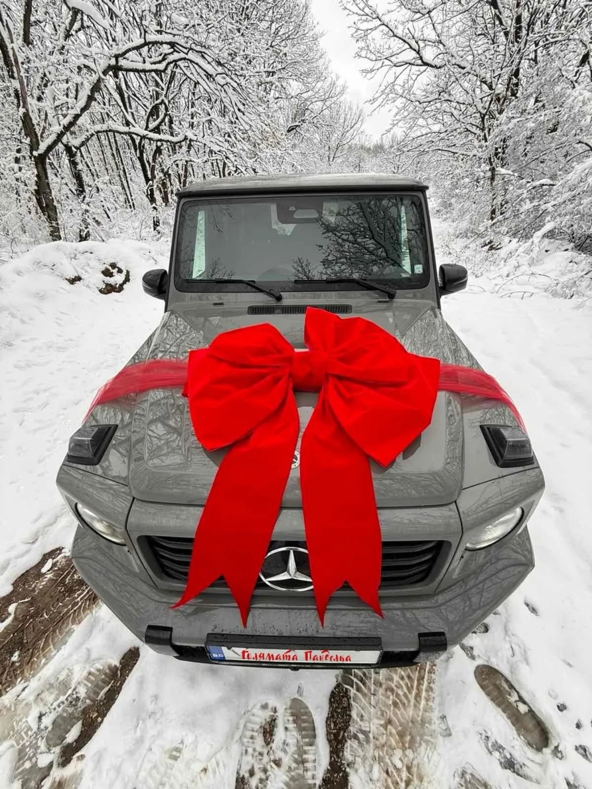 Mercedes G-класа с червена велурена панделка в снега